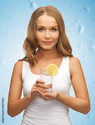 Photo: woman with lemon slice on glass of water woman with lemon slice on glass of water