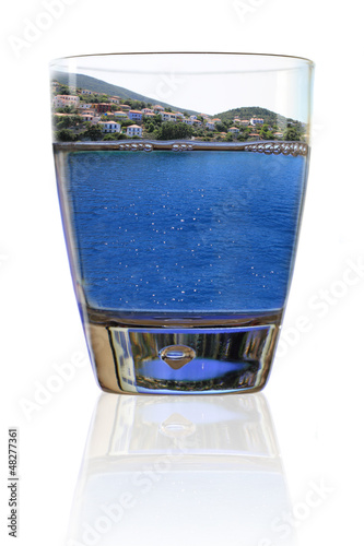 Photo: Glass of vacation. Greek island in a glass of water Glass of vacation. Greek island in a glass of water