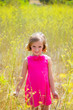 child kid girl in spring yellow flowers field and pink dress