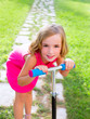 child happy girl playing with scooter in garden