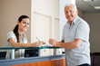 Senior Man Standing At Hospital Reception