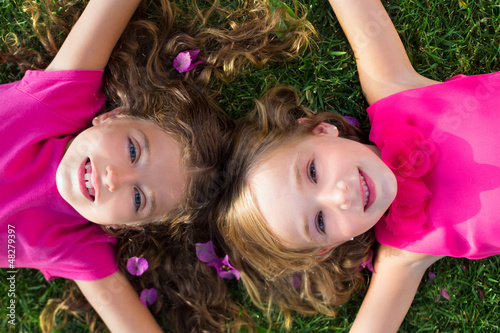 Photo: children friend girls lying on garden grass smiling children friend girls lying on garden grass smiling