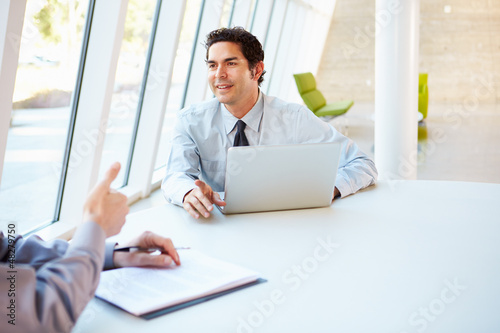 Photo: Two Businessmen Having Meeting Around Table In Modern Office Two Businessmen Having Meeting Around Table In Modern Office