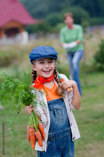 Photo: Vegetable garden - lovely girl with bunch of carrots Vegetable garden - lovely girl with bunch of carrots