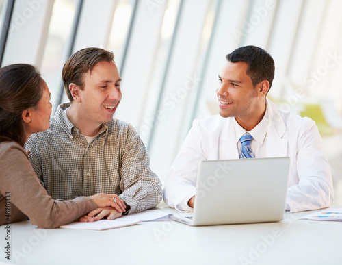 Photo: Doctor Using Laptop Discussing Treatment With Patients Doctor Using Laptop Discussing Treatment With Patients