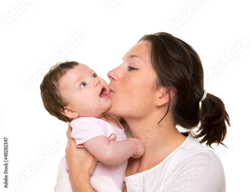 Photo: Beautiful mother kissing baby girl hug on white Beautiful mother kissing baby girl hug on white
