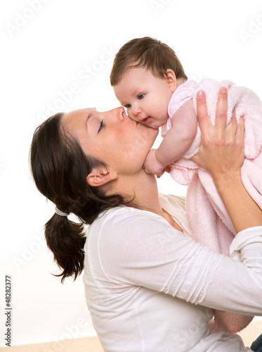 Photo: Beautiful mother kissing baby girl hug on white Beautiful mother kissing baby girl hug on white