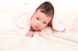 baby girl under hidden pink blanket on white fur