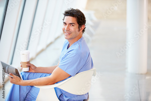 Photo: Doctor Using Digital Tablet On Coffee Break In Hospital Doctor Using Digital Tablet On Coffee Break In Hospital