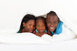 happy african american family lying under duvet on bed