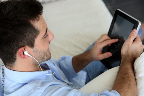 Photo: Man sitting in sofa using smartphone and tablet Man sitting in sofa using smartphone and tablet