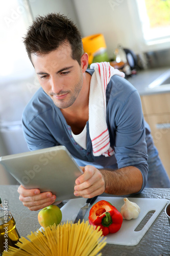 Photo: Closeup of smiling man in kitchen using tablet Closeup of smiling man in kitchen using tablet