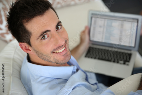 Photo: Upper view of young man using laptop computer at home Upper view of young man using laptop computer at home
