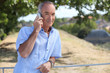 Grey-haired man making telephone call in park