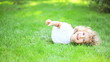 Happy child lying on green grass outdoors in spring park