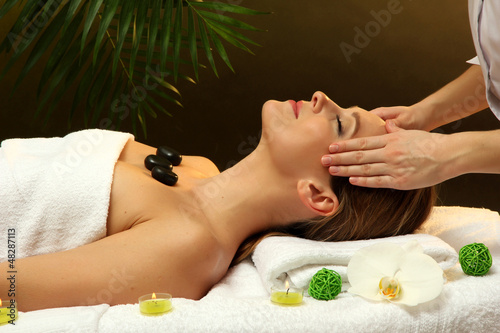 Photo: Portrait of beautiful woman with spa stones taking head massage Portrait of beautiful woman with spa stones taking head massage