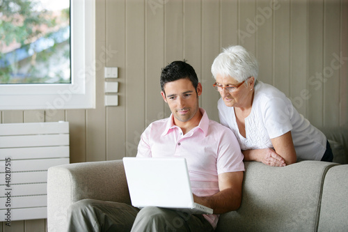 Photo: Young man and a senior woman looking at a laptop Young man and a senior woman looking at a laptop