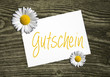 2 Blüten auf Holzwand mit Karte Gutschein