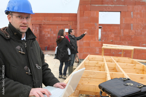 Photo: Couple standing by future home Couple standing by future home