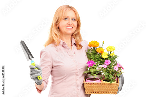Photo: A female gardener holding flowers and gardening equipment A female gardener holding flowers and gardening equipment