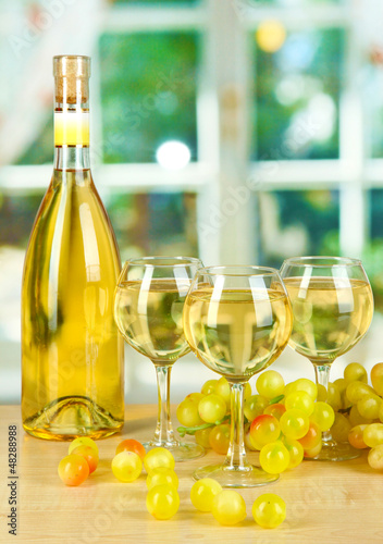 Photo: White wine in glass with bottle on window background White wine in glass with bottle on window background