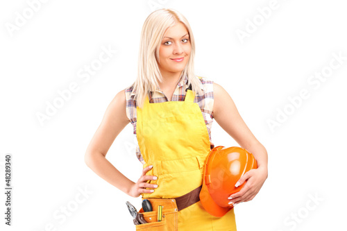Photo: A smiling female worker with a tool belt holding helmet A smiling female worker with a tool belt holding helmet