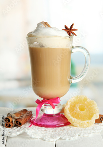 Photo: Fragrant coffee latte in glass cup with spices, on wooden table Fragrant coffee latte in glass cup with spices, on wooden table