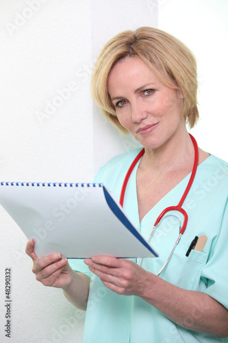 Photo: A nurse reading a file. A nurse reading a file.