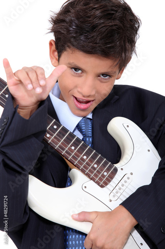 Photo: a little boy playing guitar and doing the horn sign a little boy playing guitar and doing the horn sign