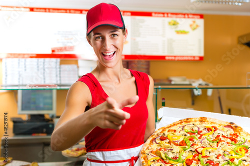 Photo: Woman holding a whole pizza in hand Woman holding a whole pizza in hand
