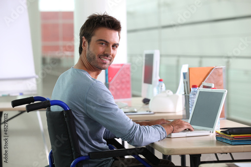 Photo: Man sitting at desk in wheelchair Man sitting at desk in wheelchair