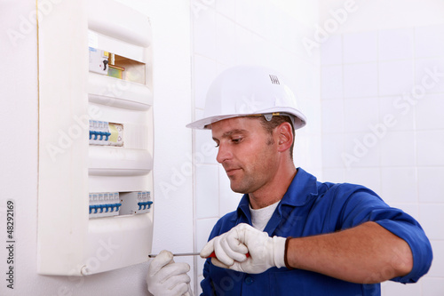 Photo: Man repairing a circuit breaker Man repairing a circuit breaker