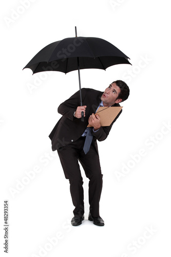 Photo: Businessman discovering a hole in his umbrella Businessman discovering a hole in his umbrella