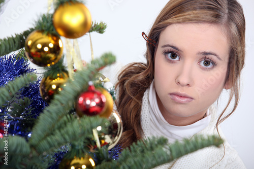 Photo: woman posing next to a Christmas tree woman posing next to a Christmas tree