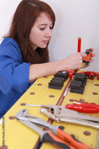 Photo: Female plumber cutting copper pipe Female plumber cutting copper pipe