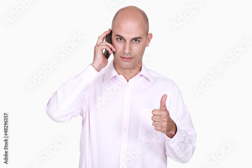 Photo: Man talking on the phone and giving the thumb's up Man talking on the phone and giving the thumb's up