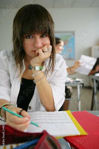 Photo: Bored teenager working on her homework Bored teenager working on her homework