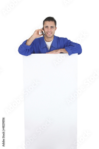 Photo: Electrician stood by blank poster surrounded by equipment Electrician stood by blank poster surrounded by equipment