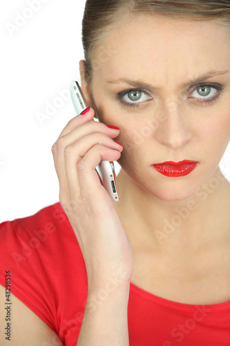 Photo: Annoyed woman in red using a cellphone Annoyed woman in red using a cellphone