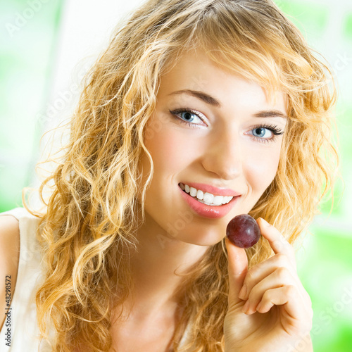 Photo: Young happy woman eating grape Young happy woman eating grape