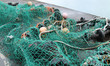 A Green Fishing Net with Floats on a Harbour Wall.