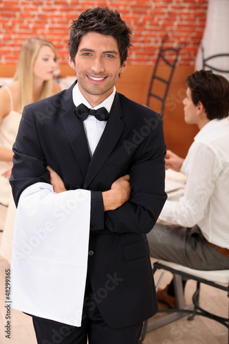 Photo: waiter facing the camera, behind a couple at restaurant waiter facing the camera, behind a couple at restaurant