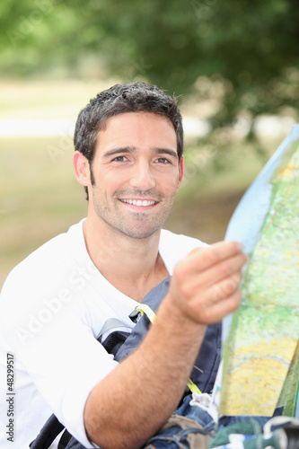 Photo: 30 years old man watching a map in the forest 30 years old man watching a map in the forest