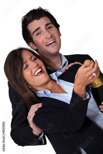 Photo: Laughing business couple celebrating with champagne Laughing business couple celebrating with champagne