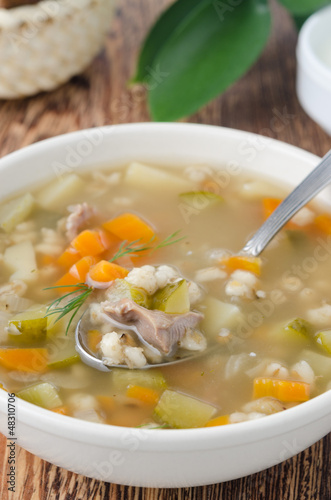 Photo: Russian soup rassolnik in a white bowl, spoon of soup closeup Russian soup rassolnik in a white bowl, spoon of soup closeup