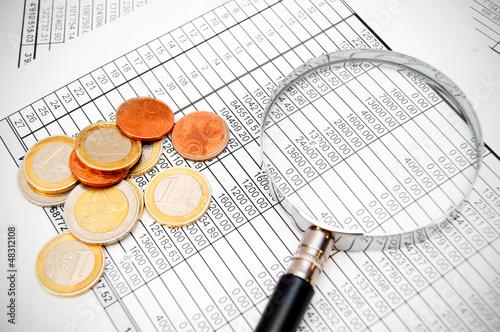 Photo: Magnifier and coins on documents. Magnifier and coins on documents.