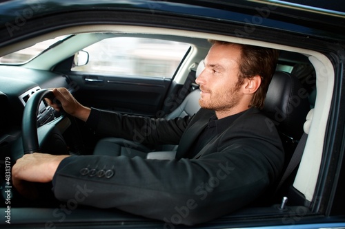 Photo: Young man driving luxury car smiling Young man driving luxury car smiling