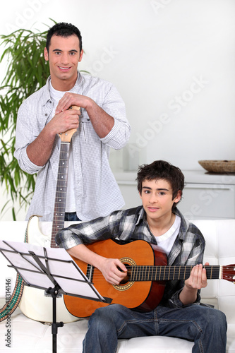 Photo: Man teaching teenage boy the guitar Man teaching teenage boy the guitar