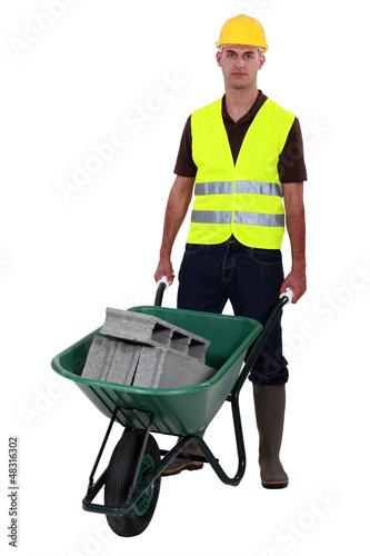 Photo: Man pushing waste material in wheelbarrow Man pushing waste material in wheelbarrow