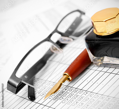 Photo: Glasses, pen and ink on documents. Glasses, pen and ink on documents.